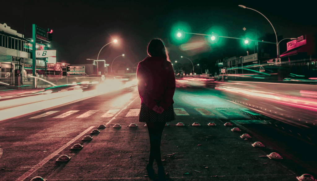 Woman walking alone on a dark Mexico City street illuminated by glowing neon lights — evoking the cinematic tension and solitude explored in books and films about Mexico City.
