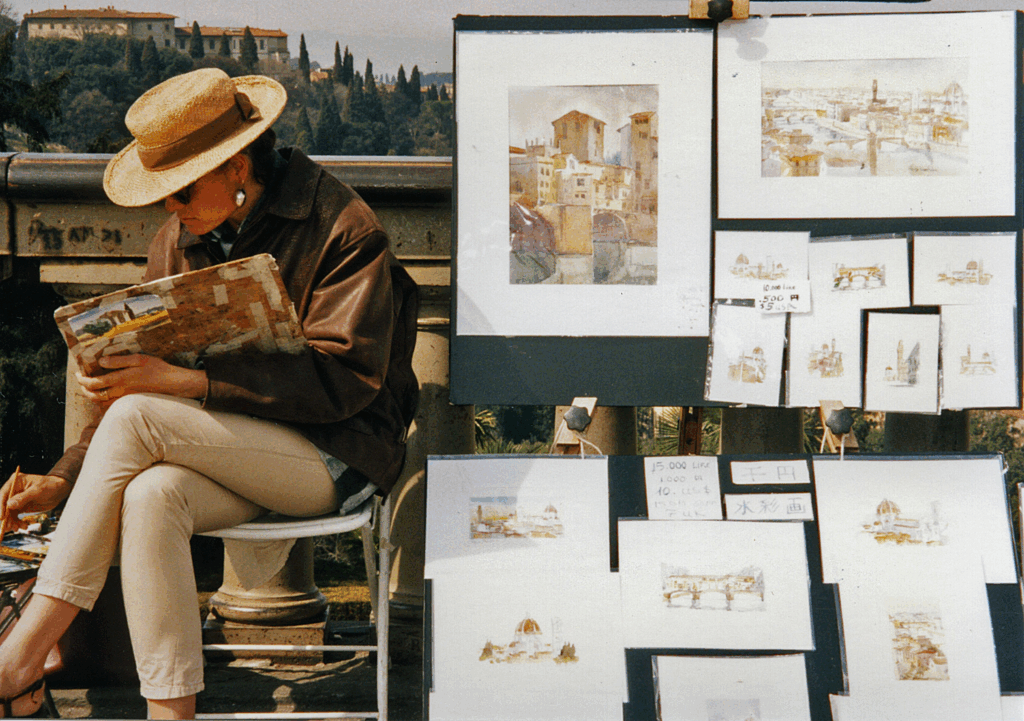 Female artist selling paintings on a Florence street, showcasing Tuscany’s creative culture and artisan traditions.