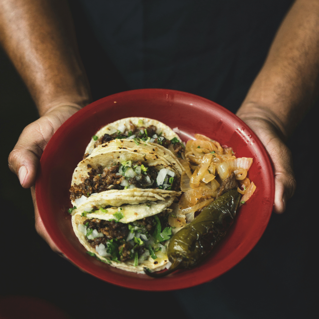 Man holding a plate of tacos, a dish frequently highlighted in food shows about Mexico City. 