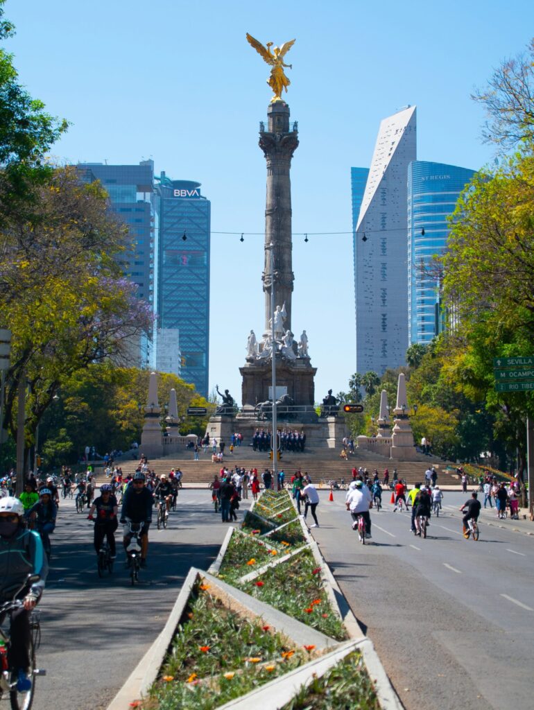 Cyclists riding along Paseo de la Reforma, with the Angel of Independence monument in view and Chapultepec Park nearby — a serene, car-free morning in Mexico City