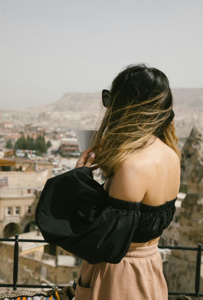 Chic woman enjoying her morning coffee on a balcony with sweeping city views.